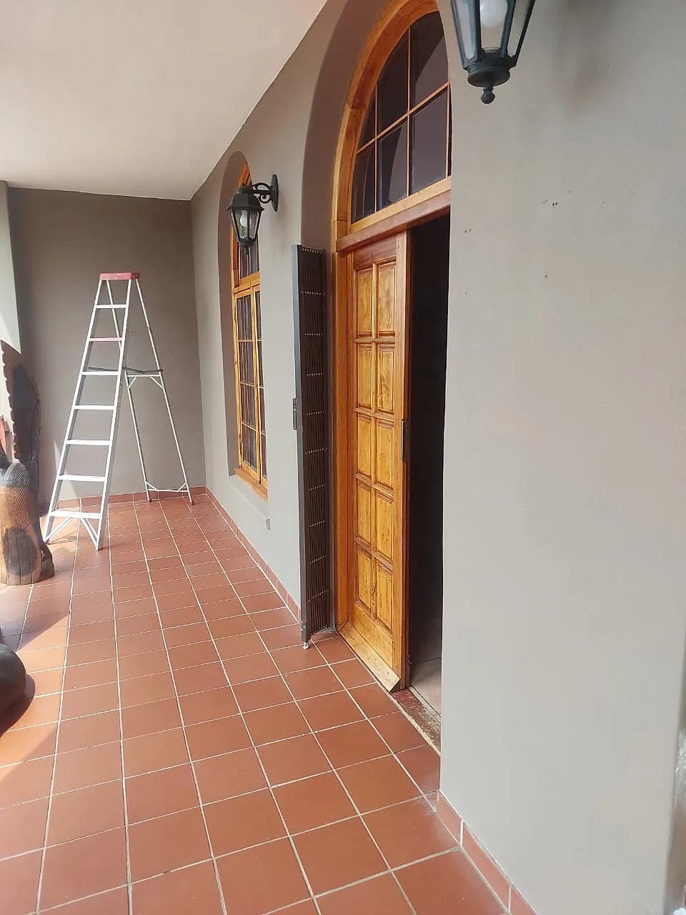 Varnished front door and arched window frames on a tiled verandah
