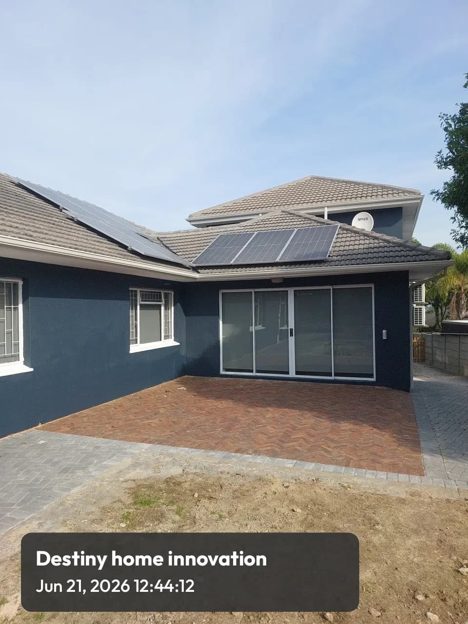 Single storey home painted charcoal with new paving and solar panels