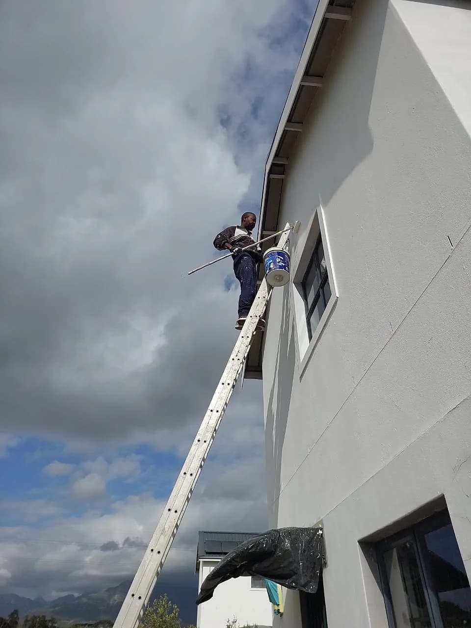 Destiny Home Innovation painter on a ladder painting an exterior wall