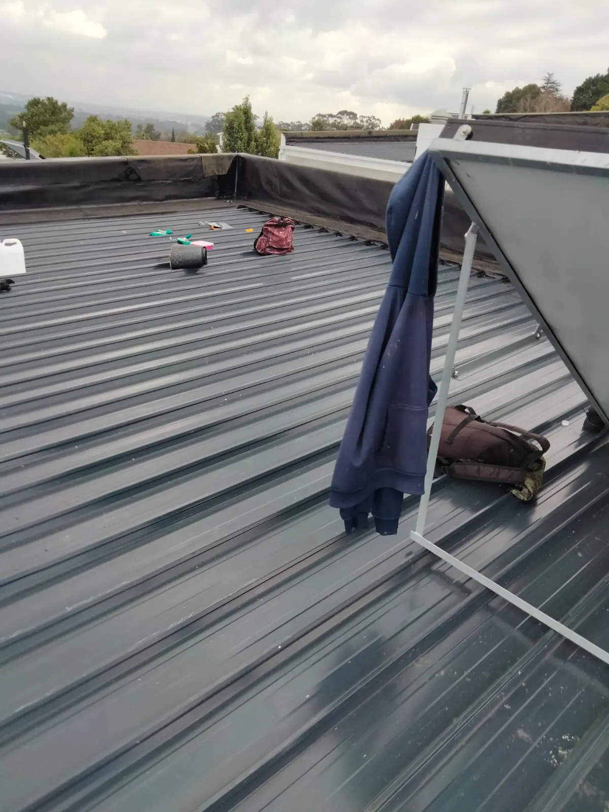 Roof coating and flashing work on a flat IBR roof with parapet walls